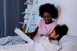 © LIGHTFIELD STUDIOS - african american mother reading daughter in evening