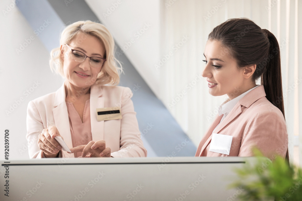 Female receptionist teaching trainee in hotel