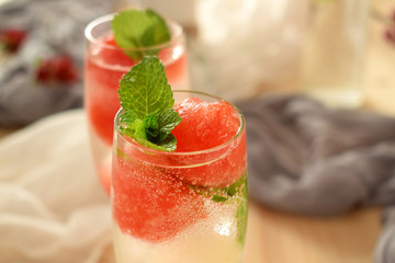 Sparkling cocktail with watermelon and melon ball-shaped pieces and ice and decorated with mint