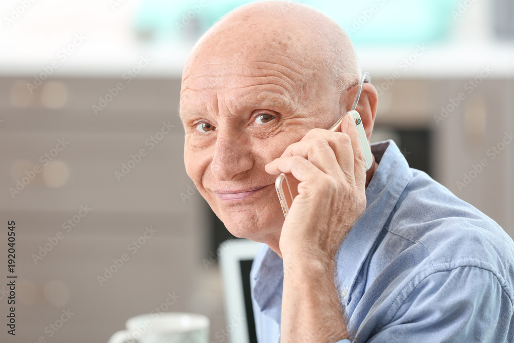 Hearing impaired man talking on phone at home