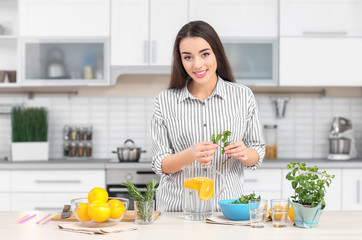 Wall Mural - Young woman preparing tasty lemonade in kitchen