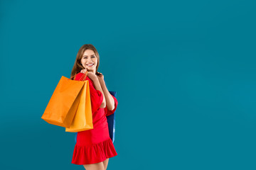 Wall Mural - Beautiful young woman with shopping bags on color background