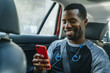 © Inti St Clair/Blend Images - Smiling Black man texting on cell phone in car