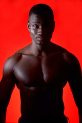 Wall Mural - portrait of an african man shirtless on red background