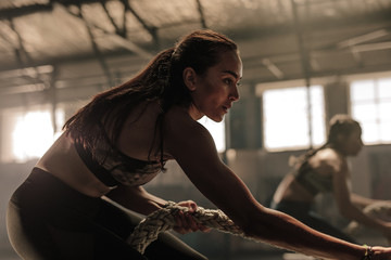 Fitness females pulling heavy rope at gym