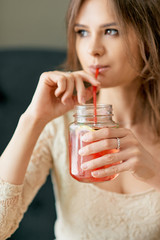 Wall Mural - Yong beautiful woman drinks strawberry lemonade with red drinking straw