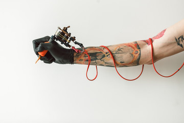 Wall Mural - Man's hand holding tattoo machine on white background. the red wires