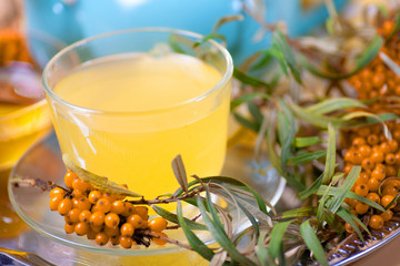 Healing sea-buckthorn tea delicious aromatic full of vitamin and microelements of bright yellow color with berries and leaves of the sea buckthorn fruit on a white background.