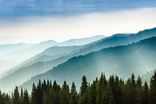 Majestic Landscape Of Summer Mountains. A View Of The Misty Slopes Of The Mountains In The Distance. Morning Misty Coniferous Forest Hills In Fog And Rays Of Sunlight. Travel Background.