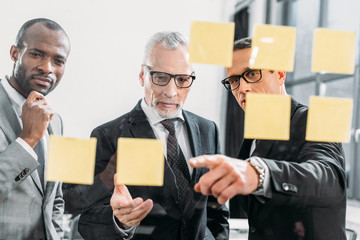 Wall Mural - multicultural businessmen looking at notes during meeting in office