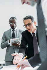 Wall Mural - partial view of multicultural businessmen discussing new plan on meeting in office