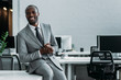 © LIGHTFIELD STUDIOS - smiling african american businessman sitting on table in office