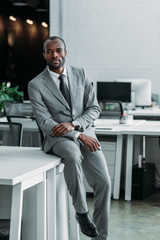 african american businessman sitting on table in office