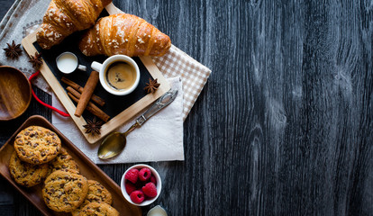 Top view of a wood table full of cakes, fruits, coffee, biscuits, spices and more