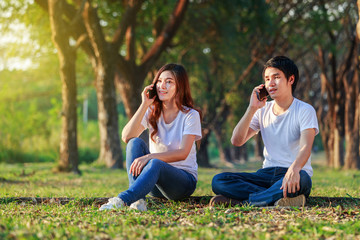 Wall Mural - couple talking on mobile phone in the park