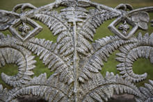 Isolated View Of Decorative Fern Pattern Wrought Iron Work Against Out Of Focus Green Grass In Background