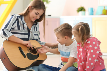 Poster - Mother playing guitar for her little children at home