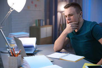 Canvas Print - Tired student doing homework indoors late at night