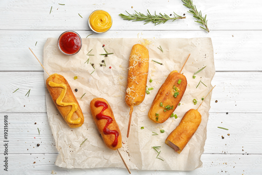 Tasty corn dogs with sauces on table