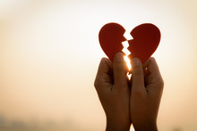 Close Up And Silhouette Of Woman Hand Holding Broken Paper Red Heart On Sunset. Love, Wedding And Valentines Day Concept.