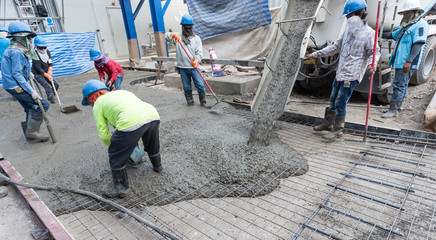 Workers at the construction site placing concrete slab