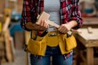 © Wavebreak Media - Mid section of woman holding mallet with tool belt around her