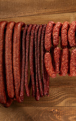 Wall Mural - Composition of different type of sausage hanged on wooden background