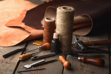 Wall Mural - Set of leather craft tools on wooden background. Workplace for shoemaker. Piece of hide and working handmade tools on a work table.