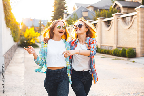 Two best friends are laughing and walking in city. Stock Photo | Adobe Stock