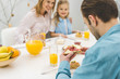 © LIGHTFIELD STUDIOS - selective focus of man having breakfast together with family at home