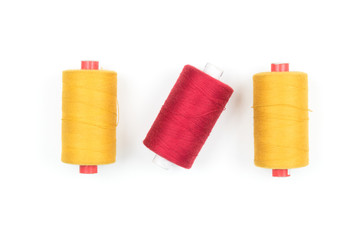 Wall Mural - Yellow and red thread coils on white background, sewing and tailoring supplies