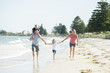 © Wordley Calvo Stock - young happy and beautiful family mother father holding hand of son and daughter walking joyful on the beach enjoying Summer holidays