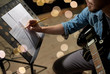 © Syda Productions - man with guitar writing to music book at studio