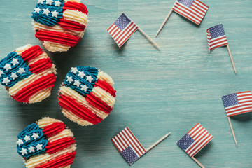 Wall Mural - flat lay with arranged cupcakes and american flags on wooden tabletop, presidents day celebration concept