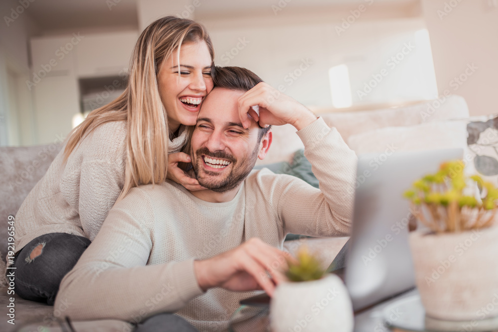 Happy young couple with laptop at home - obrazy, fototapety, plakaty 