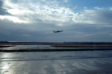 The plane takes off early in the morning from the aerodrome runway against the backdrop of the dawn and the sea in the distance