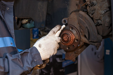 Wall Mural - The man is repairing the disc brake machine, close-up. Disk brake repair in the car.