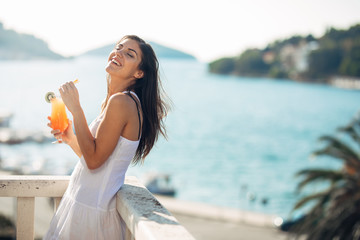 Carefree young female on holiday summer vacation having fun on a sunny day,relaxing with ocean view,listening waves,enjoying summer with refreshing drink.Love summer.Deserved vacation