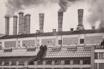 Heat station in the city. Smoking pipes against blue sky. Aluminum pipes of old Industrial building of factory. Pollution and ecology, vintage background