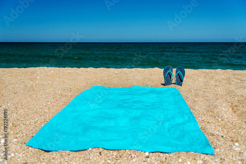 Fotografía Blue sandal flip flop and towel on yellow sand