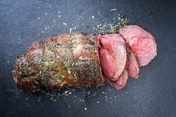 Wall Mural - Barbecue dry aged haunch of venison with herbs as close-up on a black board