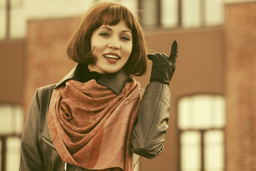 Happy beautiful fashion woman in red scarf and leather coat in city street