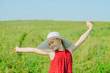 © anastasiia agafonova - Little girl in red dress and white hat with large brim stands on green meadow on sunny day