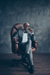 © deagreez - Full length portrait of brutal old man in tux holding glass with whiskey, smoke cigar, looking to the side, sitting in chair, leg on leg, side view, profile face shares, money, stock, gray background