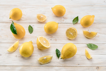 Wall Mural - Ripe lemons and lemon leaves on wooden background. Top view.