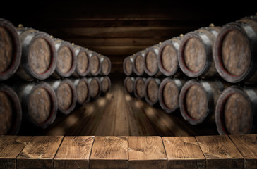 Wall Mural - Old wooden table top and oak wine barrels at the background.