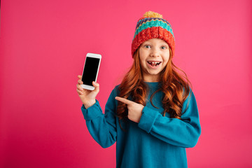 Wall Mural - Surprised happy girl showing smartphone with blank screen and smiling isolated