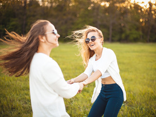 Wall Mural - Two lovely women are dancing on the lawn at sunset