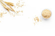 Cereals concept. Oatmeal in bowl near sprigs of wheat on white background top view copy space