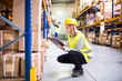 © Halfpoint - Woman warehouse worker with clipboard.